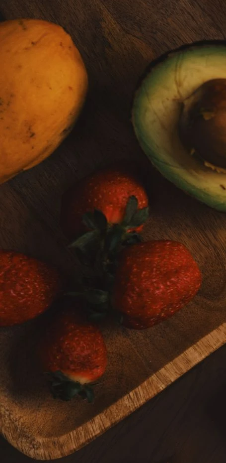 Mango, aguacate y fresas sobre una tabla de madera